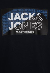 Námořnické bavlněné tričko s černým obdélníkovým grafikou, na které je bílé a modré textové logo "JACK & JONES" a geografické souřadnice na spodní části.
