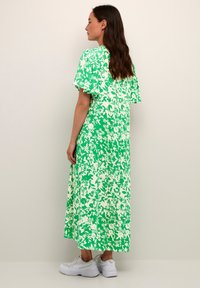 Zelena midi obleka s cvetnim vzorcem in kratkimi napihnjenimi rokavi, izdelana iz lahkotnega materiala, s sproščenim krojem in dolžino do gležnjev.