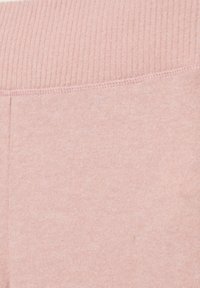Un tessuto rosa chiaro presenta una texture a coste nella parte superiore, con una finitura liscia sottostante. Le cuciture appaiono pulite e coerenti in tutto.