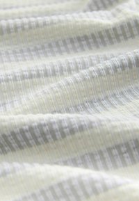 Woven fabric in light cream with subtle gray stripes; features a textured surface with fine lines and a soft, flexible appearance.