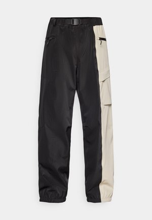 Zwarte en beige waterdichte cargobroek met zijzakken, elastische tailleband en omgeslagen zoom. Gemaakt van gladde, lichte stof.