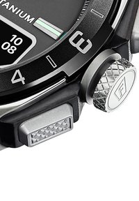 Zegarek na rękę wykonany z tytanu, z czarną okrągłą tarczą, srebrnymi akcentami, teksturowanym przyciskiem oraz żłobioną koroną po prawej stronie.