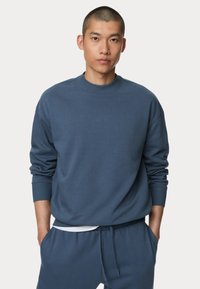 Felpa blu in morbido tessuto, con collo rotondo, polsini a costine e vestibilità comoda. Abbinata a pantaloni sportivi blu coordinati.
