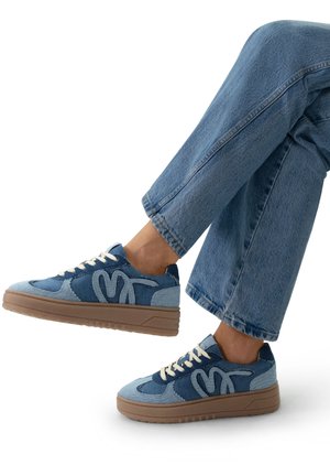 Denim sneakers featuring a mix of medium and light blue shades, textured fabric, beige laces, and a chunky brown sole.