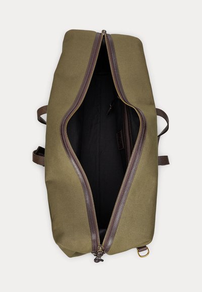 Grande borsa da viaggio verde oliva con rifiniture in pelle marrone scuro e cerniera dorata parzialmente aperta che mostra l'interno in tessuto nero vuoto.