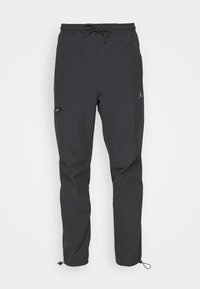 Zwarte sportbroek van lichtgewicht stof, met een trekkoord in de taille, een ritszak en taps toelopende boorden met trekkoorden.