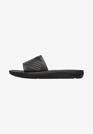 Black slide sandals with a textured strap featuring wave patterns. Soft rubber material and a contoured sole for comfort.