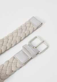 Ceinture tressée en daim gris clair avec des accents en cuir. Présente une boucle en métal argenté et une finition lisse sur la section en cuir.