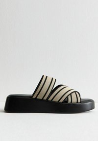 Beige en zwarte gestreepte slip-on sandalen met een dikke zwarte platformzool. Voorzien van brede stoffen banden voor ondersteuning en comfort.