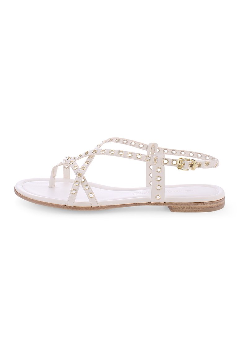 Weiße Sandalen mit flacher Sohle, ausgestattet mit mehreren überkreuzten Riemen mit runden Ausschnitten und goldenen Hardware-Akzenten. Hellbraune strukturierte Sohle.