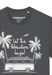 Grijze katoenen t-shirt met een ronde halslijn, versierd met een witte afbeelding van een vintage bus en palmbomen, vergezeld van de tekst "Laat het avontuur beginnen!"