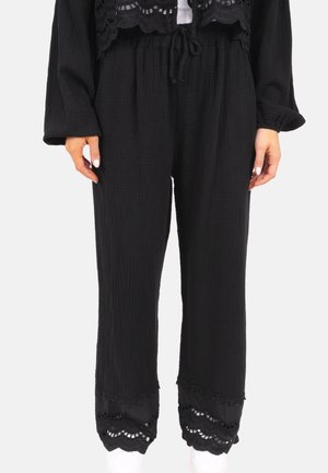 Pantalons noirs en tissu texturé, dotés d'une taille élastique, d'un cordon de serrage et d'accents en dentelle aux poignets. Design à coupe décontractée.