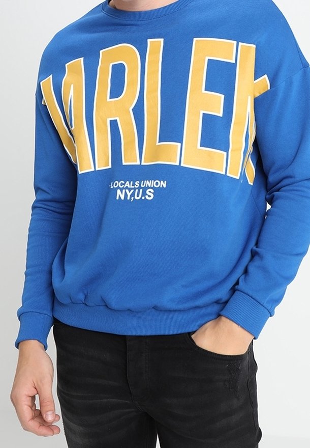 Sudadera azul con grandes letras amarillas que dicen "HARLEM", con un detalle adicional en blanco abajo, puños y dobladillo de canalé.