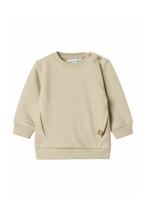 Beige puuvillane sviiter ribblikuga, pika varrukaga ja küljetaskuga detailiga. Väikesed nööbid õlal, et hõlbustada selga panemist.