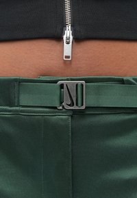 Πράσινο παντελόνι με απαλό, υφή υφάσματος, που διαθέτει κομψή γκρι αγκράφα και ασημένιο φερμουάρ στη μέση.