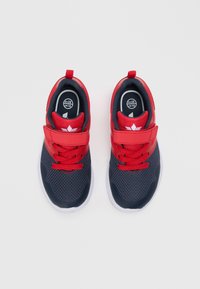 Červené a námořnické atletické boty z síťovinového materiálu, zaoblený špička, odpovídající červené tkaničky, nastavitelný popruh a bílé gumové podrážky.