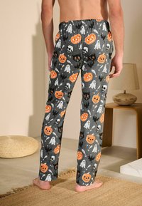 Crne hlače imaju uzorak utemeljen na Noći vještica s narančastim bundevama, bijelim duhovima, crnim mačkama i lubanjama na sivoj pozadini.
