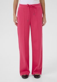 Pantalons en tissu rose vif avec une coupe décontractée, taille à cordon de serrage et poches latérales, comportant des détails de plis sur le devant.
