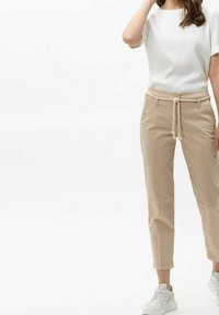 Pantalons cropped en mélange de coton beige avec taille à cordon, poches latérales et coupe décontractée, associés à un haut blanc uni à manches courtes.