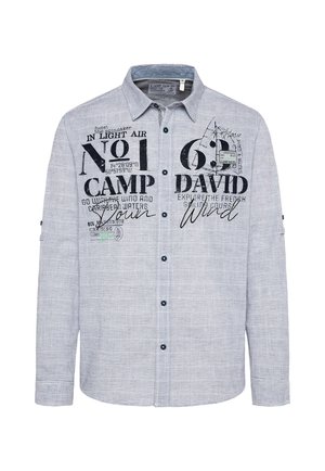Camisa abotonada de color azul claro con textura estampada. Presenta texto impreso en negro y acentos, además de un cuello tipo puntiagudo y mangas largas.