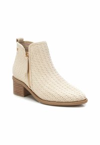 Botín de tobillo tejido en beige con punta afilada, cierre lateral y tacón apilado. Superficie texturizada con acentos sutiles y suela duradera.