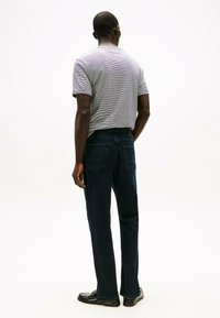 Jeans din denim de un albastru închis și un tricou gri cu dungi. Jeansii au două buzunare la spate. Tricoul are un guler rotund și mâneci scurte.