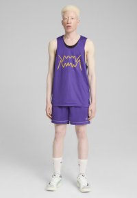 Jersey de baloncesto de malla púrpura con diseño de líneas amarillas, pantalones cortos a juego, calcetines blancos y zapatillas ligeras. Estética sencilla y deportiva.