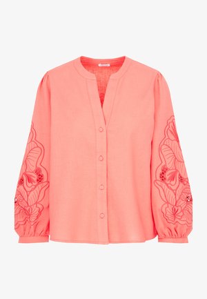 Koralowa lniana bluzka z dekoltem w serek, zapinana na guziki z długimi bufkowymi rękawami, zdobiona haftem kwiatowym wzdłuż mankietów. Gładka tekstura.