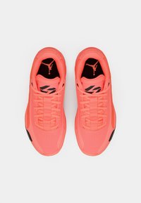 Koral atletiske sneakers med et struktureret mesh-overdel, kontrasterende sorte accenter og et fremtrædende Jumpman-logo på tungen og siden.