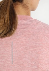 Helles pinkes Sweatshirt mit einer weichen Textur, das ein schlichtes Design und einen dezenten grauen senkrechten Streifen auf dem Rücken aufweist.