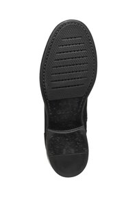 Suola di scarpa in gomma nera caratterizzata da una superficie testurizzata con scanalature orizzontali e verticali, e un logo impresso nella zona del tallone.