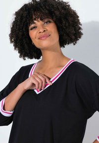 Sort V-hals top med 3/4 ærmer og kontrastfulde pink- og hvide stribedetaljer ved halsudskæringen og ærmekanterne. Glat stoftekstur.