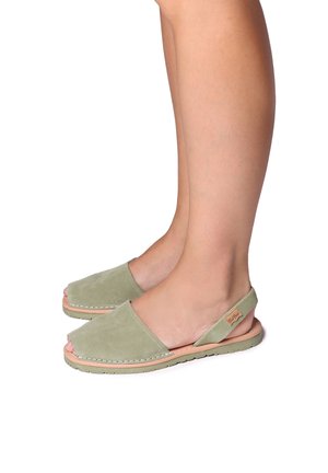 Gröna mocka slingback-sandaler med öppen tå, med ett sömnadskant och tan gummisula, som visar upp en enkel, platt design.