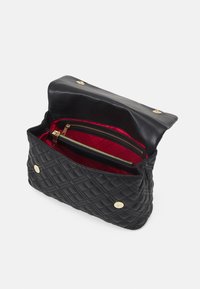 Svart quiltad läderväska med magnetförslutning, med ett rött inre och två zippered fack för organisering.