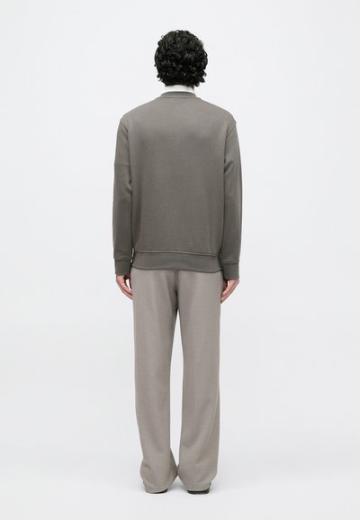Sivá mikina s dlhými rukávmi a rebrovaným lemom, v kombinácii so svetlosivými, strihanými nohavicami. Hladká, ľahká tkanina.