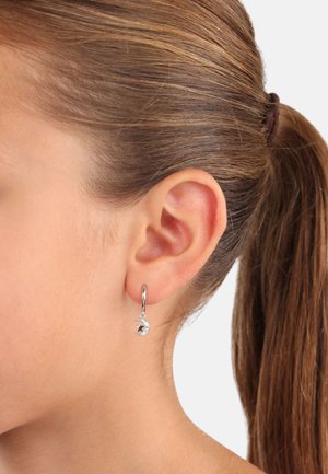 Silberne Creolen mit einem kleinen Stern- und Halbmonddesign, verziert mit klaren Edelsteinakzenten, die direkt unter dem Ohrläppchen hängen.