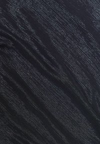 Tessuto nero con una texture scintillante, caratterizzato da strisce verticali e sottili fili metallici, che creano un effetto sottile e stratificato.