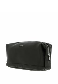 Pochette en cuir noir avec surface texturée, fermeture éclair et garnitures argentées. Présente un logo embossé à l'avant et un fond plat.