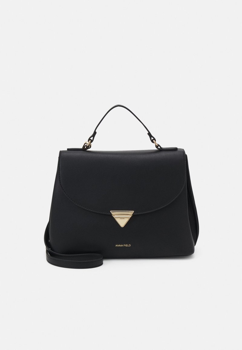 Sac à main structuré noir avec poignée supérieure, fermoir triangulaire doré et bandoulière amovible sur fond blanc.