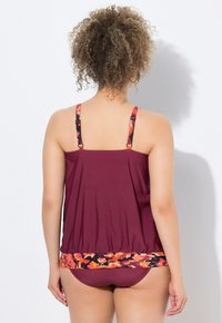 Burgundy tankini, jossa on säädettävät olkaimet ja kukkakuosiset alaosat. Sujuva pinta, suunniteltu uima-asuksi.