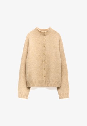 Beżowy, dziergany kardigan z wysokim kołnierzem, pełnym zapięciem na guziki z przodu oraz ściągaczem na dole. Posiada miękką teksturę i luźny krój.