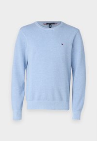 Pull bleu clair en tissu texturé avec un col rond et des poignets côtelés. Présente un petit logo sur le côté gauche de la poitrine.