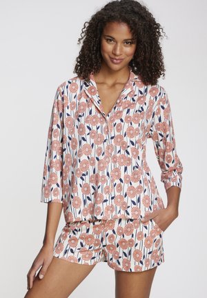 Short-sleeve pajama set in white with pink floral print and navy accents; shirt has a collar, buttons, and shorts with side pockets.