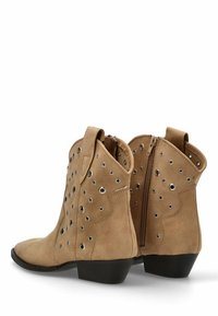 Botas cortas de ante en color marrón claro con punta afilada, presentan ojales metálicos y una cremallera lateral, montadas sobre un tacón bajo negro.