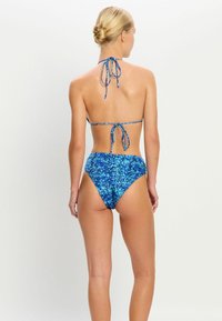 Blaue gemusterte Bikini mit Haltertop und hochgeschnittenem Unterteil. Verfügt über verstellbare Bänder und einen strukturierten, weichen Stoff.