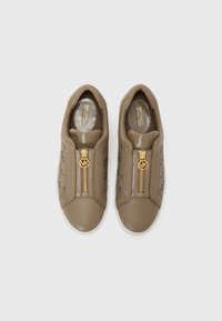 Hnedé slip-on tenisky s hladkým povrchom, zlatým zipsom na ozdobu a jemnou potlačou monogramu MK na boku. Biela gumová podrážka.