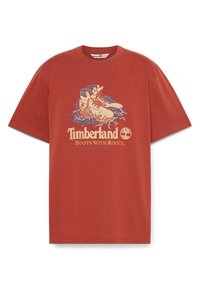 Rustfarvet bomulds t-shirt med grafisk print af støvler og løv. Har rund hals og korte ærmer. Teksten lyder "Timberland Støvler Med Rødder."