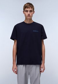 T-shirt en coton bleu marine avec col rond et manches courtes, ornée d'un petit logo bleu sur la poitrine, sur fond uni.