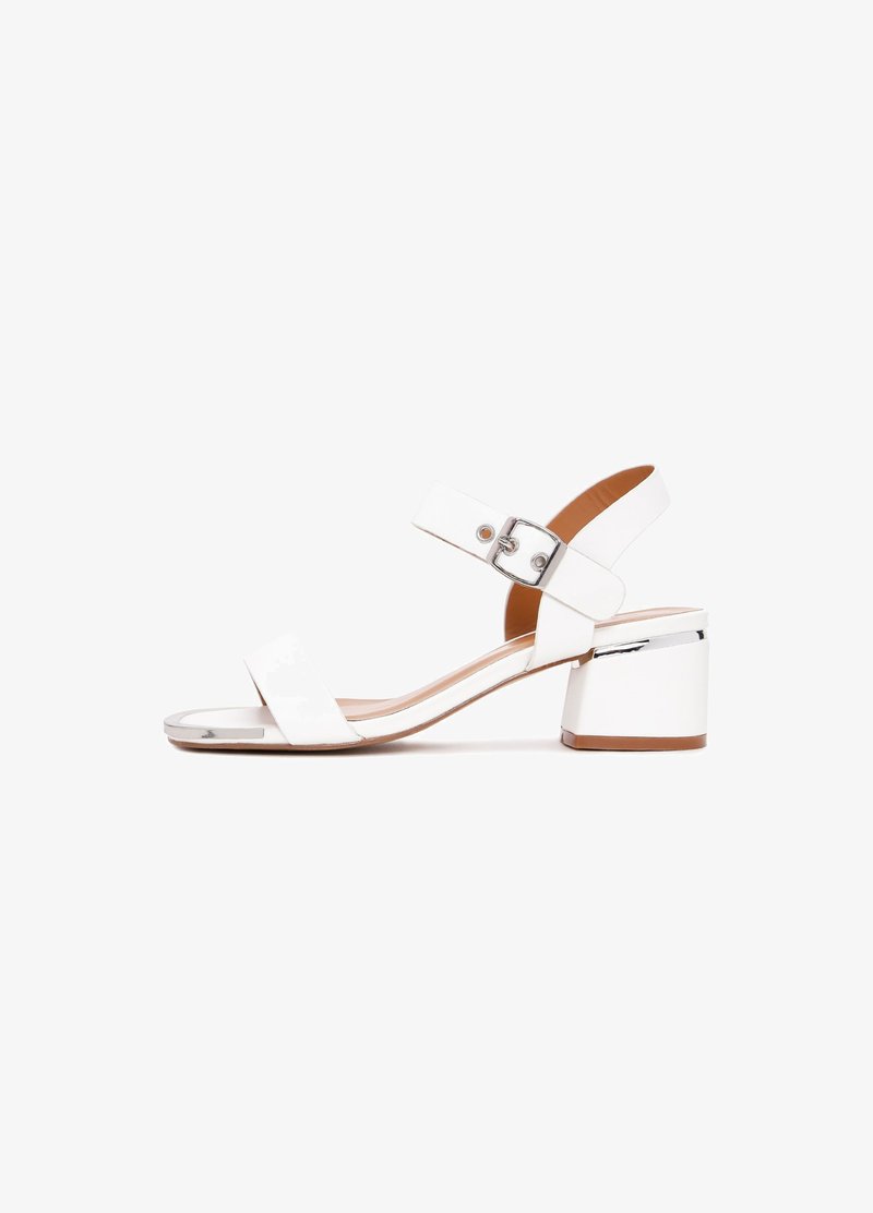 Sandales blanches à talons avec deux brides horizontales, une sangle de cheville avec boucle et un bout carré. Le talon est de forme bloc avec un accent chromé.