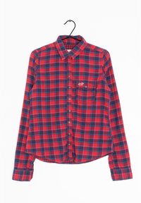 Camicia a maniche lunghe a quadri rossi e blu navy con colletto, chiusura con bottoni e taschino sul petto con un piccolo logo. Tessuto di cotone, leggermente testurizzato.